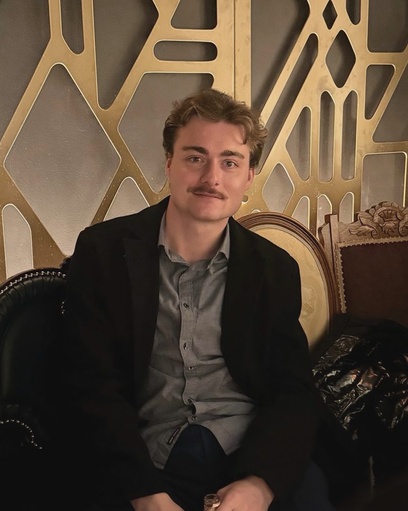 Max Smith in a dark blazer against a gold art deco wall in Des Moines, Iowa
